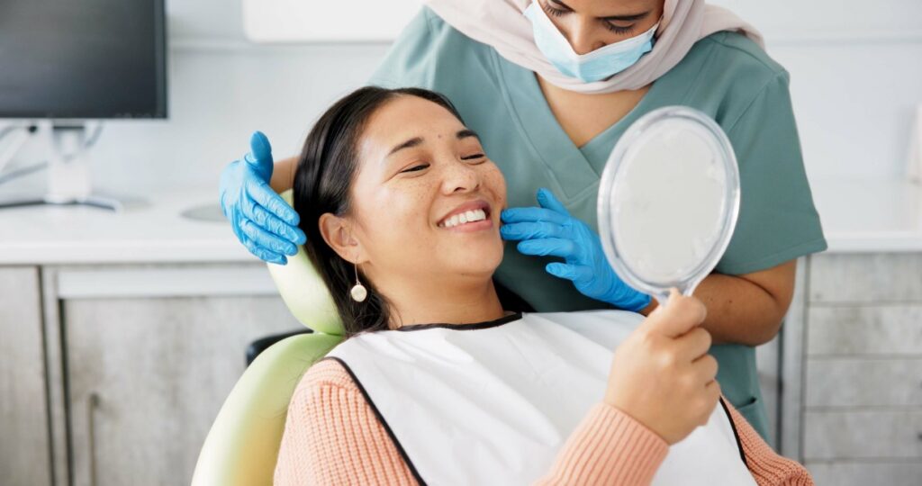 Patient checking her smile in a mirror during a dental visit